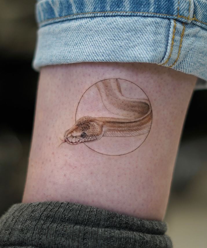 Minimalist foot tattoo in the form of a circle and a snake